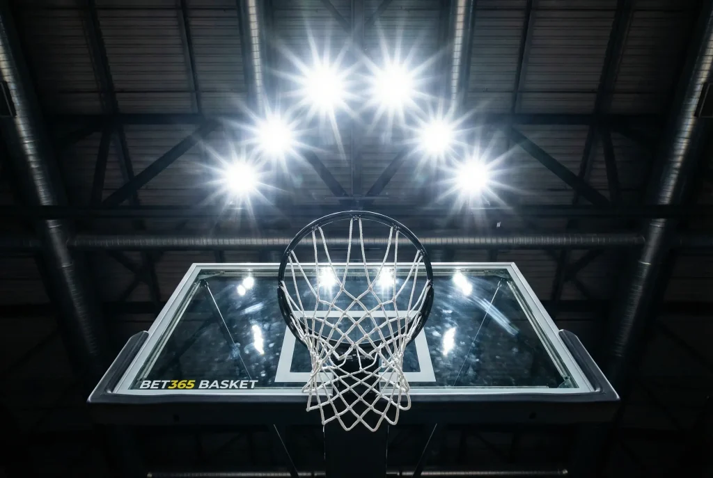 bet365 scommesse basket: campo da basket illuminato con canestro visto dal basso