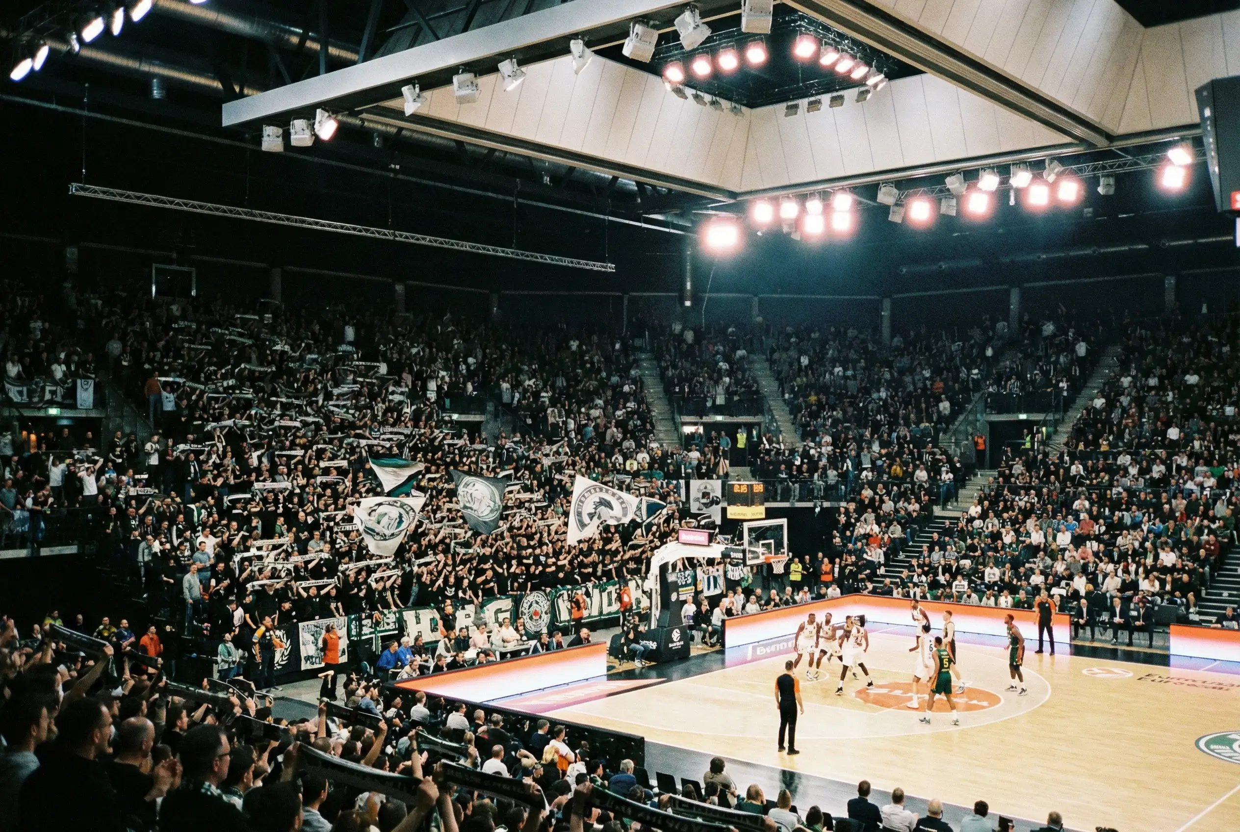 Arena di pallacanestro europea con spalti gremiti e illuminazione del campo durante una partita di Eurolega